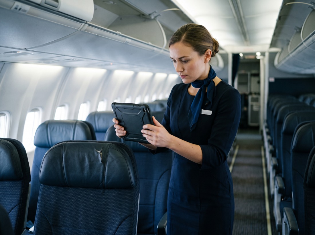 Flight attendant photographing a torn seatback with a tablet to log a cabin defect